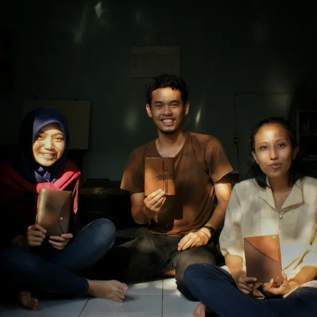 Tiga peserta duduk bersama memegang jurnal yang baru mereka jilid