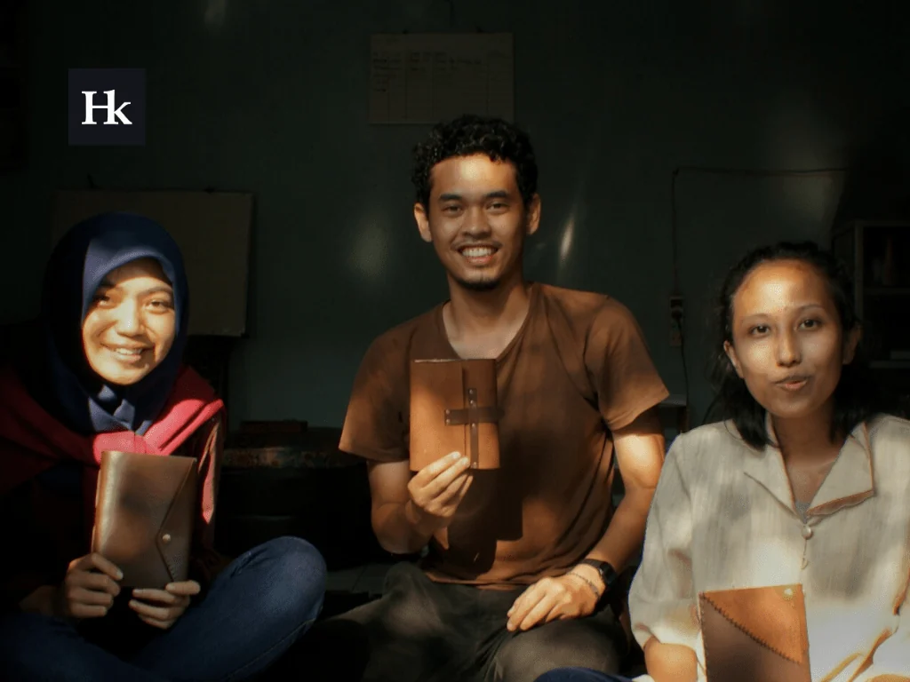 Tiga peserta kelas Hibrkraft memegang jurnal kulit yang baru mereka jahit sendiri