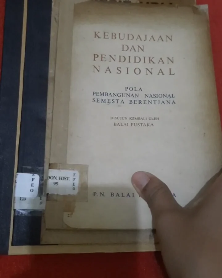 Tangan memegang buku tua yang sedang dikonservasi untuk EFEO