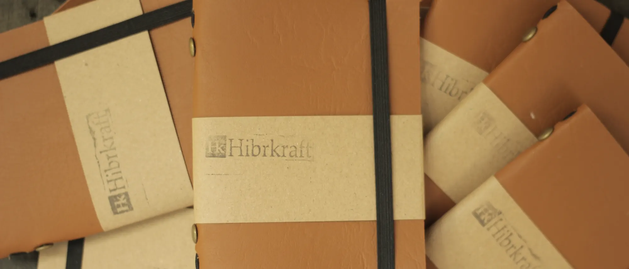Tumpukan jurnal kulit Hibrkraft dengan belly band kertas kraft