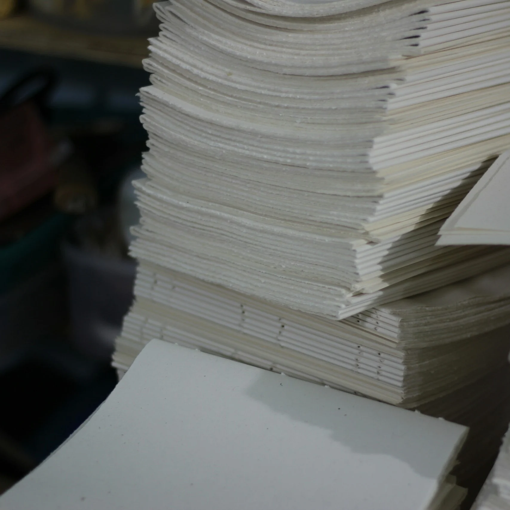 A stack of folded and punched paper signatures ready for bookbinding.