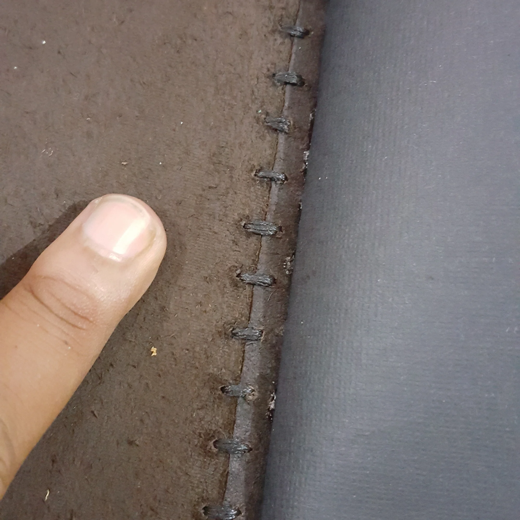 Hands holding a leather journal cover with visible coptic stitching.