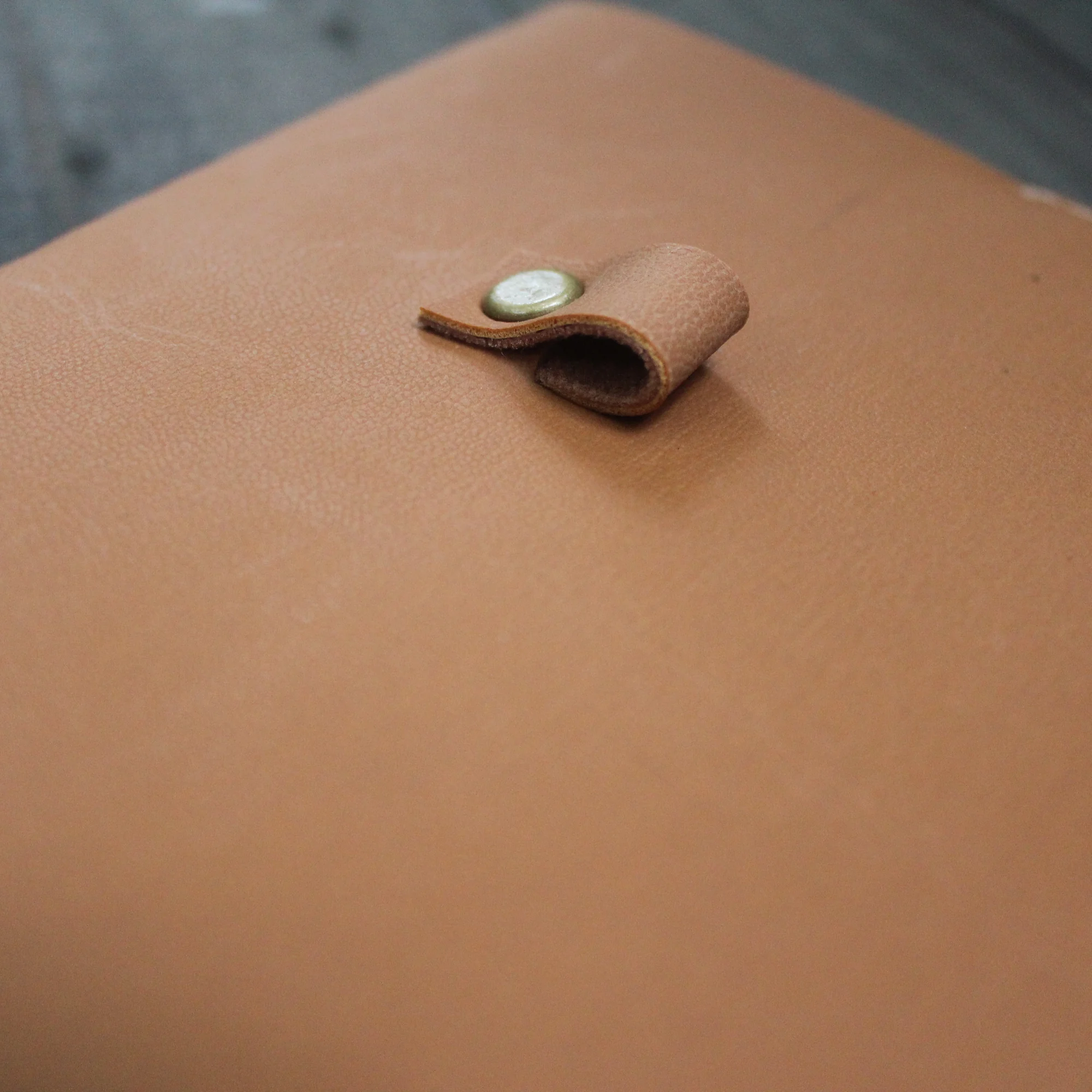 Brown leather journal cover with a snap button closure.