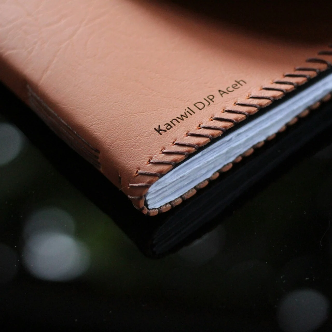 Brown leather journal with hand stitching and debossed Kanwil DJP Aceh text.