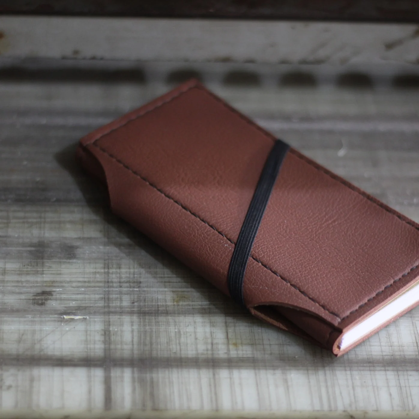 Brown leather journal with a black elastic band from the Pertamina EP project.