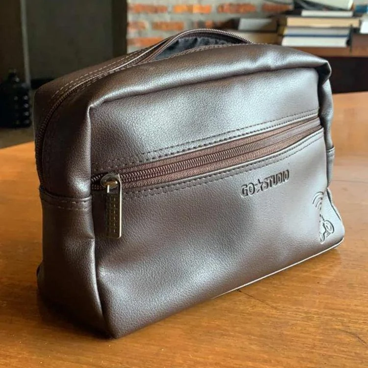 A brown leather pouch with a go-studio logo sitting on a wooden table.