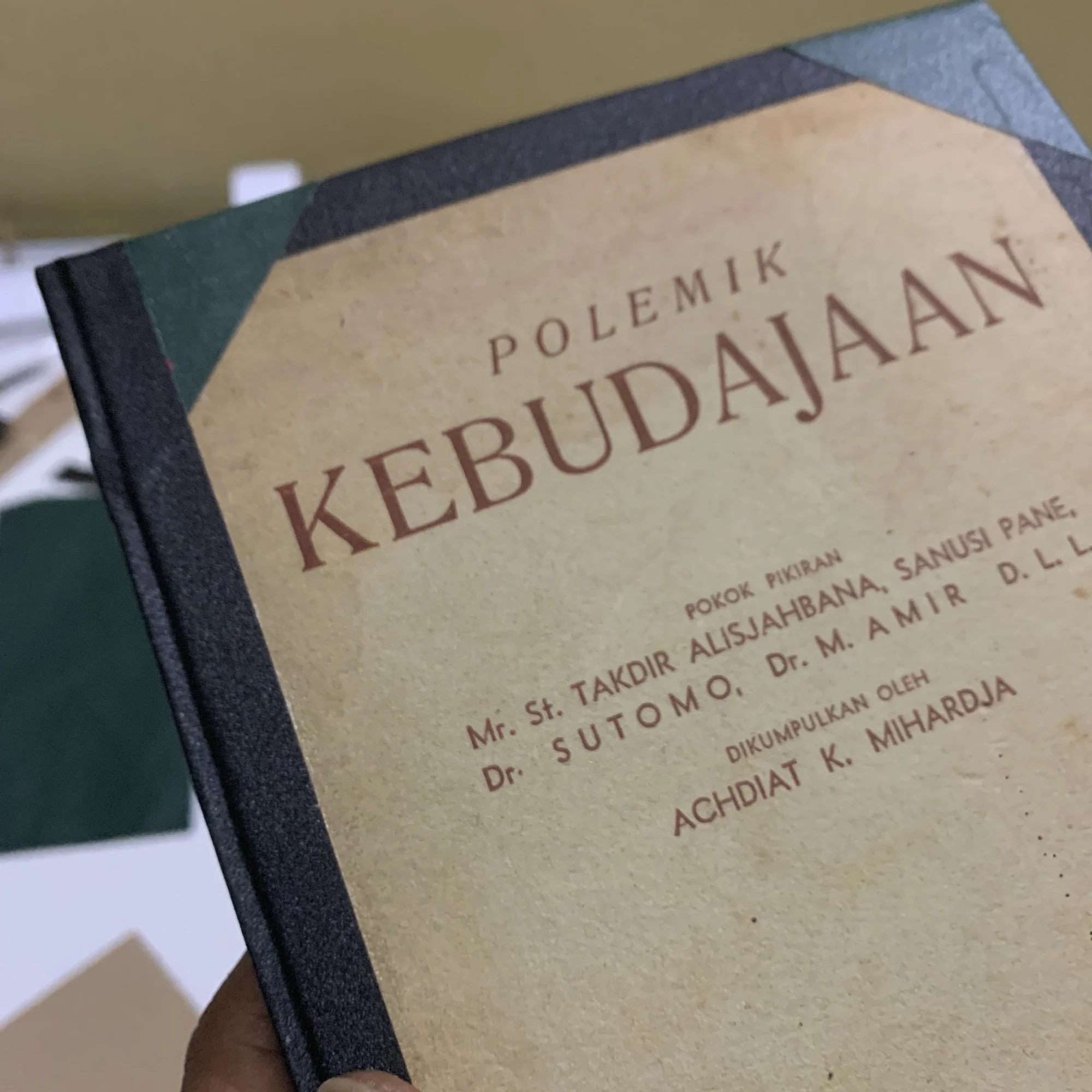 A hand holding the Polemik Kebudajaan book that has been rebound with a new cover.