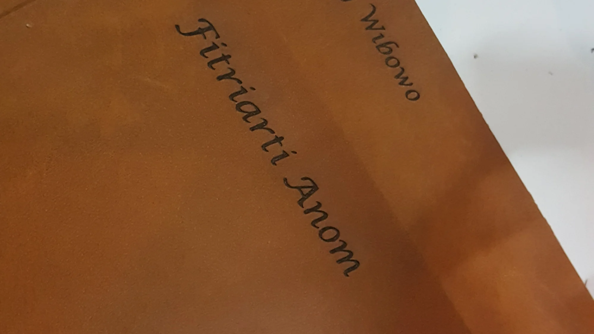Sampul kulit cokelat dengan nama pemesan terukir di permukaannya
