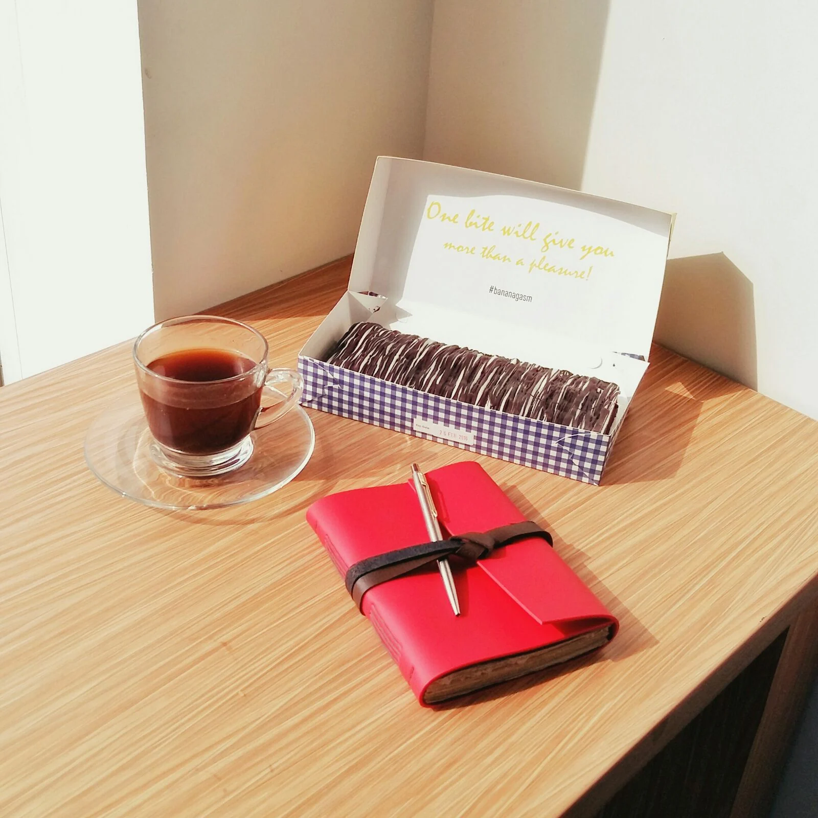 Jurnal kulit merah di meja bersama kotak dan secangkir kopi