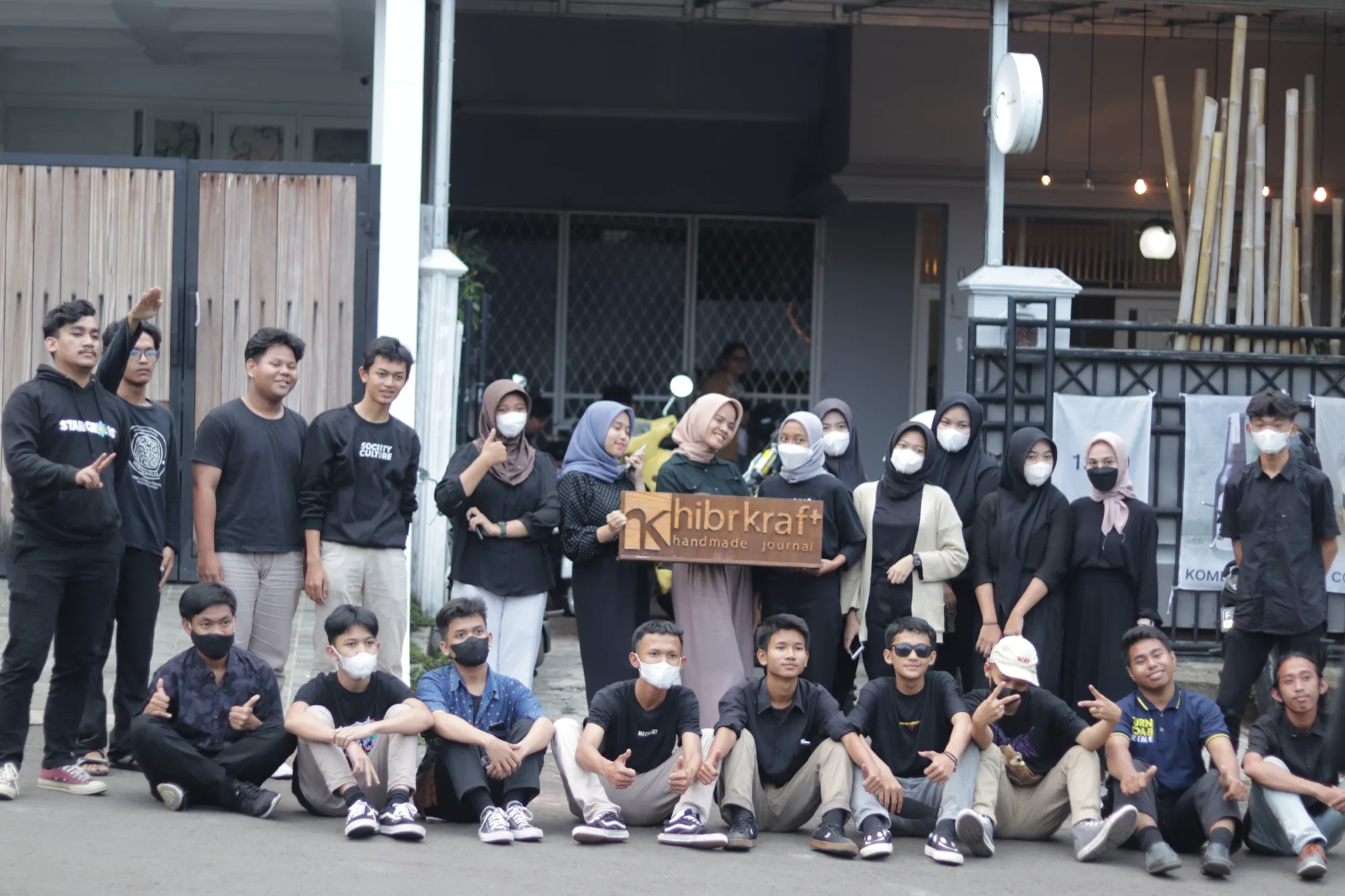 Seluruh tim Hibrkraft berfoto di depan bengkel di Bogor, memegang papan nama kayu berukir