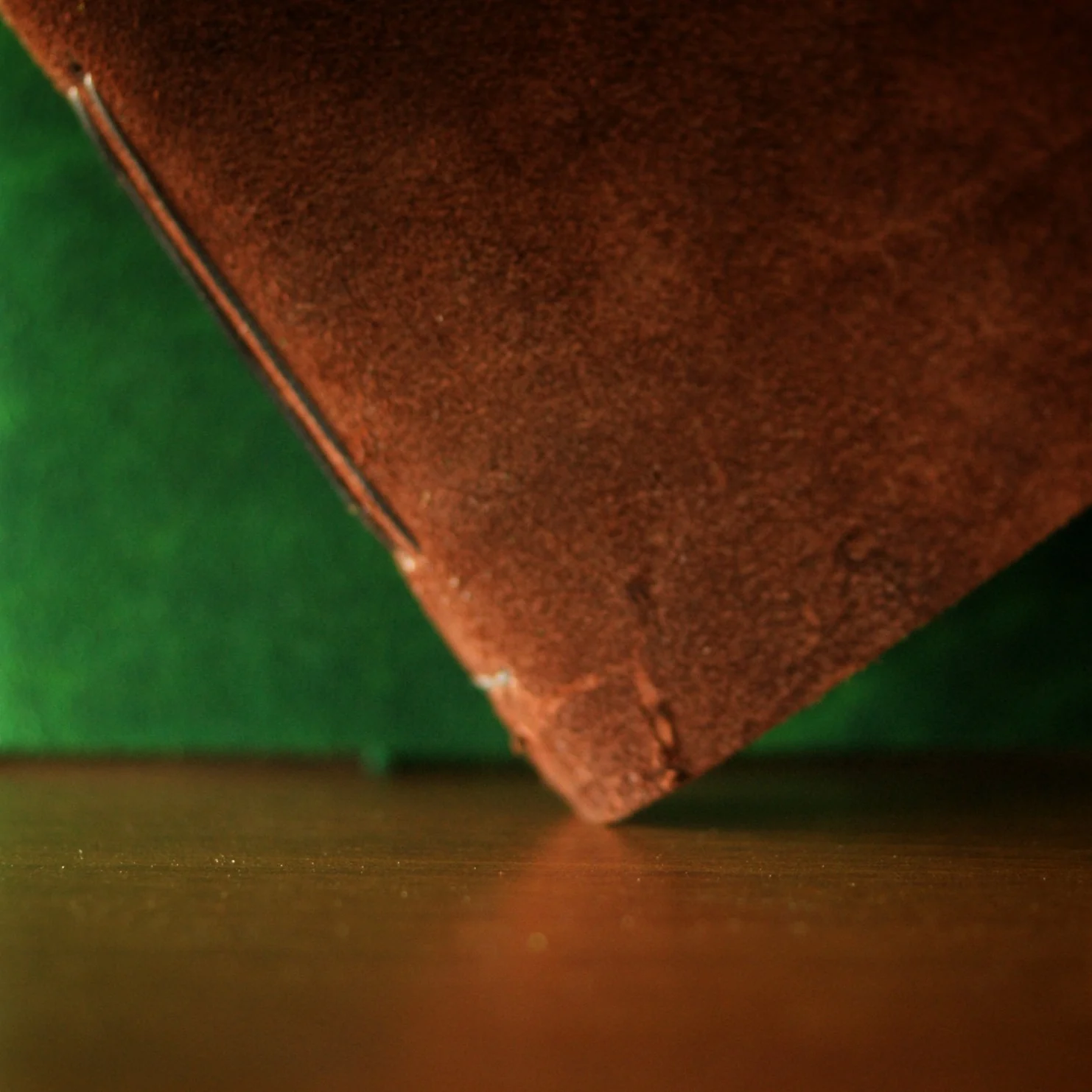Two suede journal covers in brown and green are placed on a table.