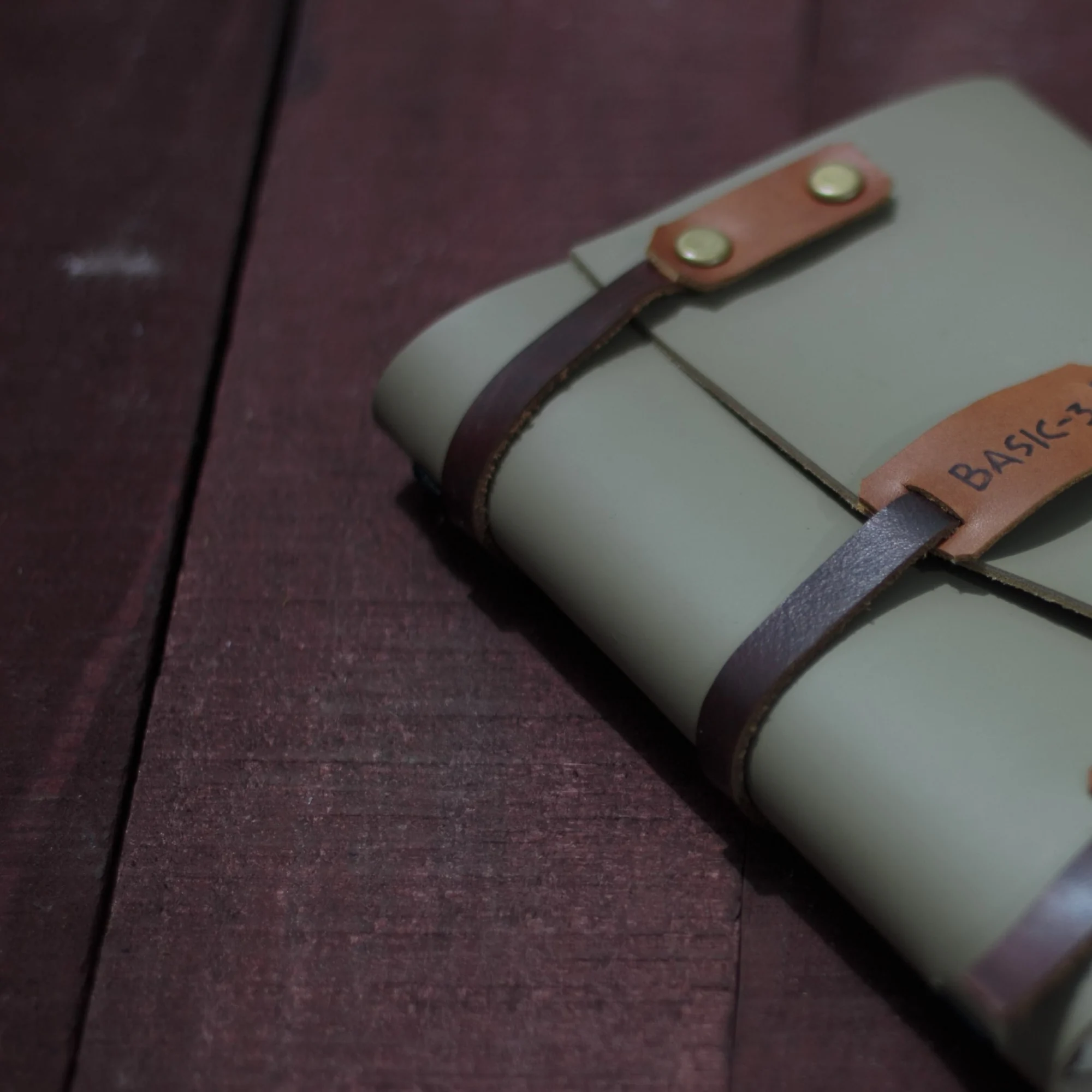 A grey leather journal with a leather strap closure and the text basic-3.