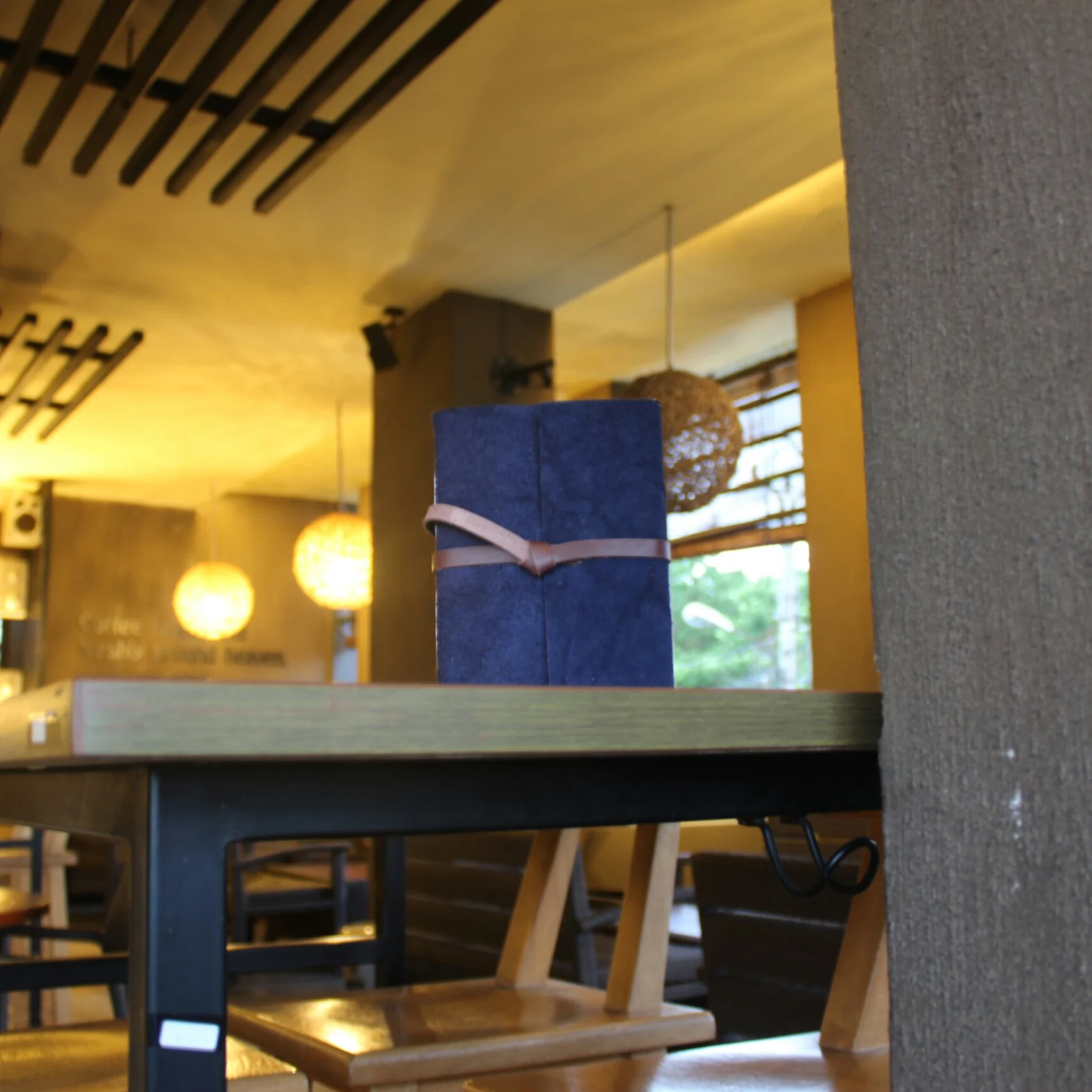A blue leather journal with a strap closure placed on a restaurant table.