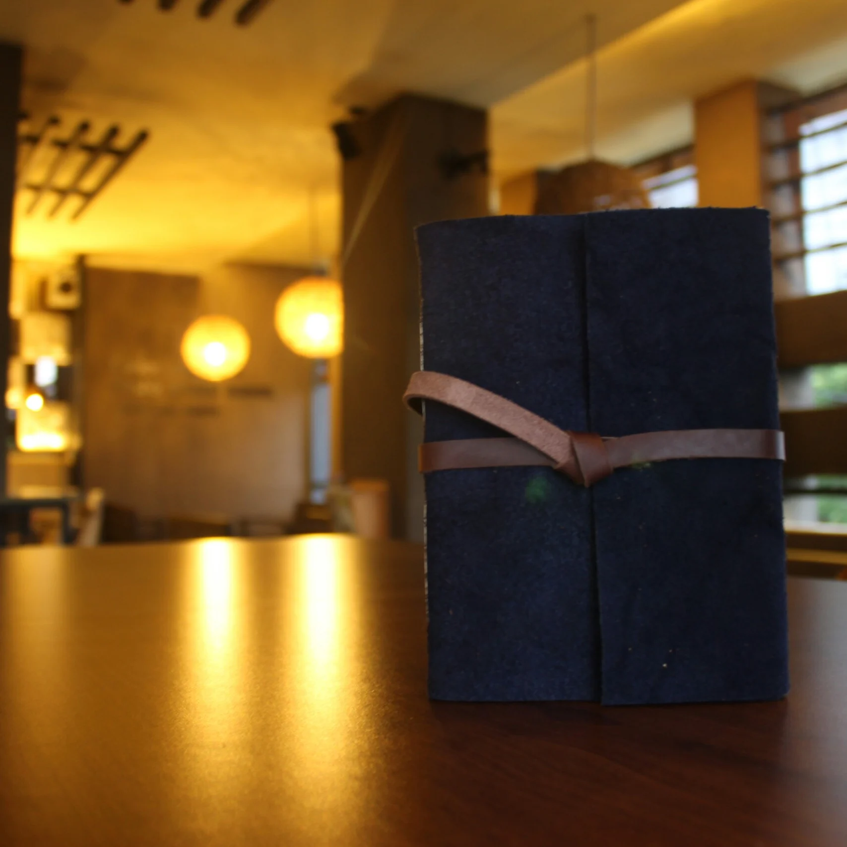 A dark leather journal with a leather tie closure sitting on a restaurant table.