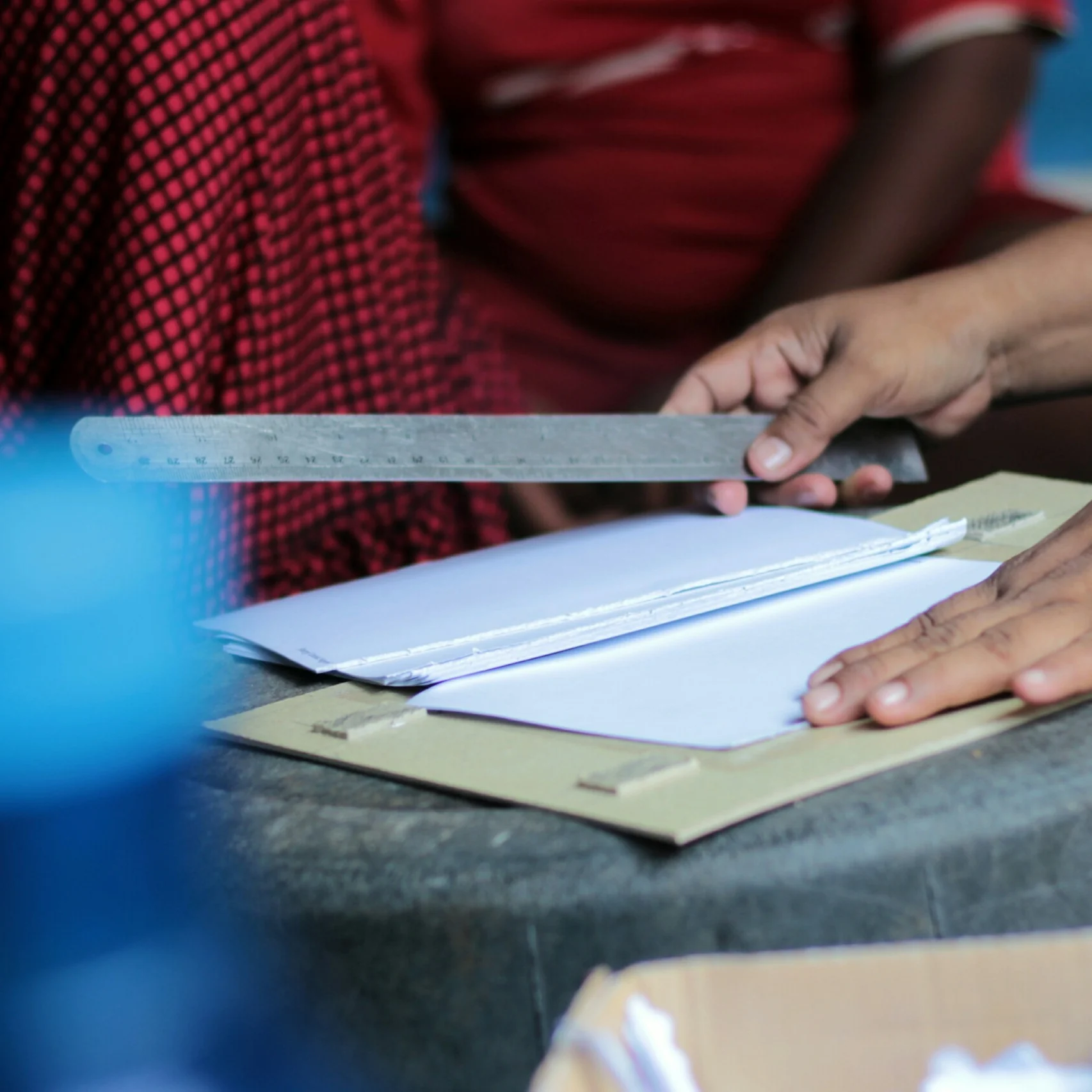 Tangan meluruskan tumpukan kertas dengan penggaris logam