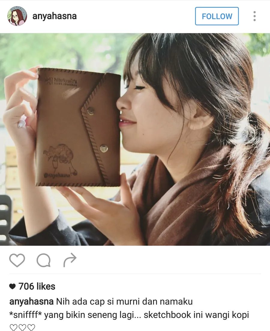Unggahan Instagram @anyahasna: sampul jurnal kulit Kava bercap gambar karakter buatannya sendiri dan tulisan @anyahasna, didekatkan ke wajahnya