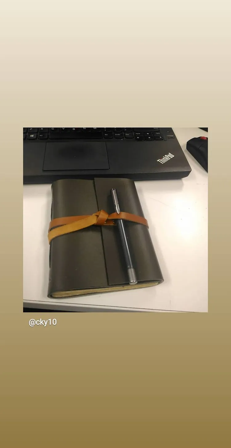 Story Instagram dari @cky10: jurnal kulit gelap bertali lilit tan di meja putih di samping laptop hitam