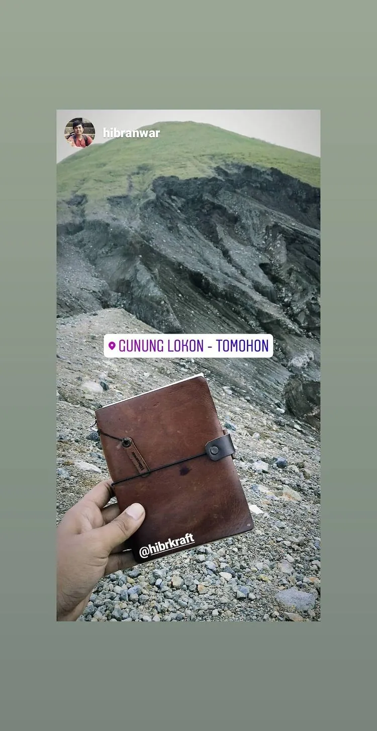 Story Instagram: jurnal kulit cokelat dipegang di atas kawah berbatu Gunung Lokon, Tomohon