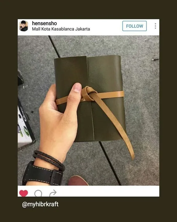 Tangan memegang jurnal kulit hijau zaitun bertali lilit tan