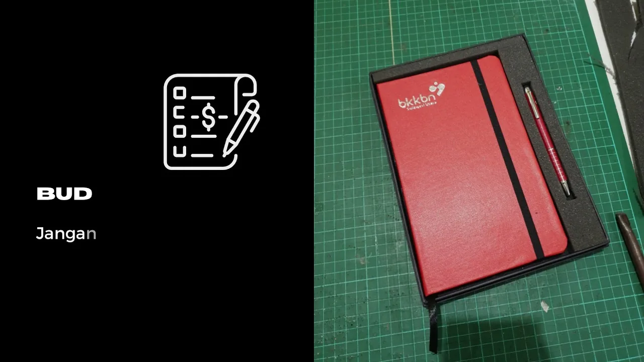 Agenda kulit merah dengan logo klien, di atas alas potong