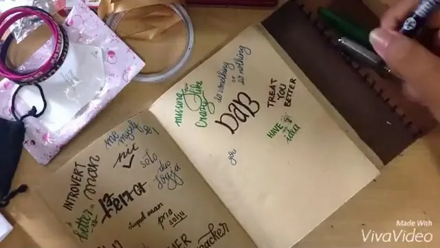 Tangan menulis lettering di halaman kertas kraft sebuah jurnal terbuka