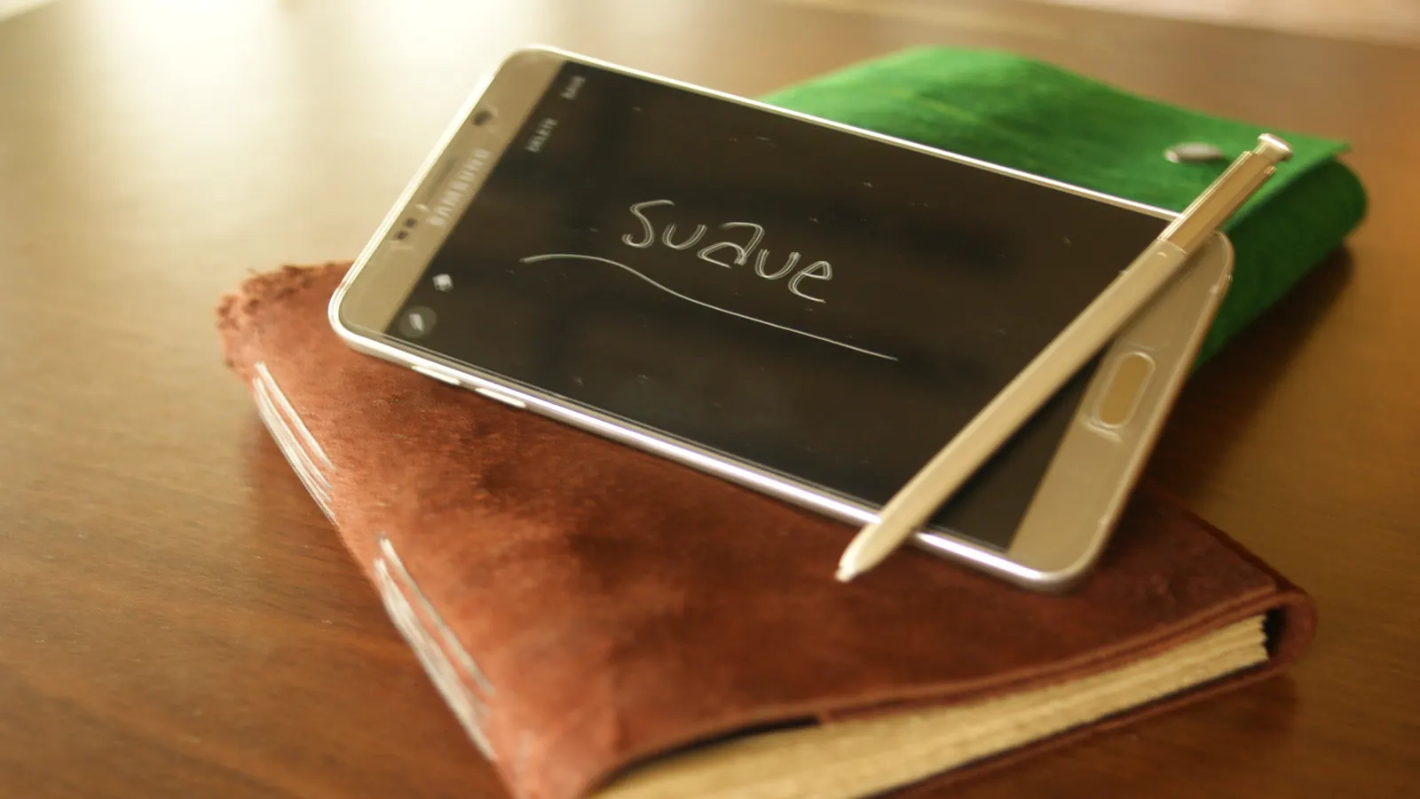 Notebook kulit suave Hibrkraft di atas meja bersama smartphone dan stylus.