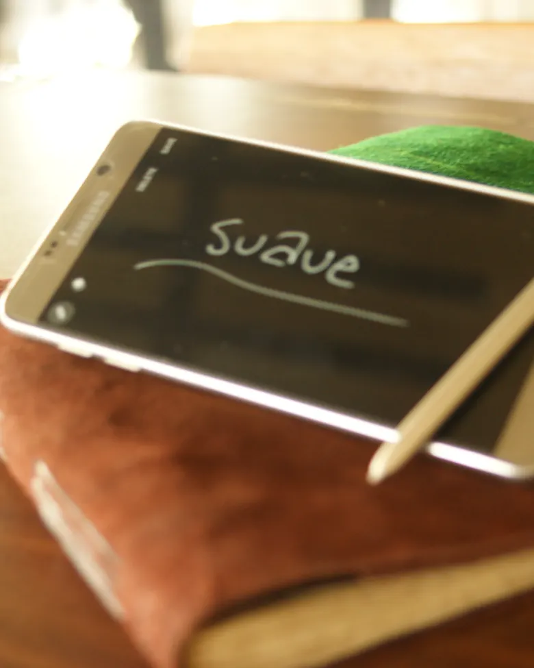 Smartphone diletakkan di atas tumpukan jurnal kulit suave