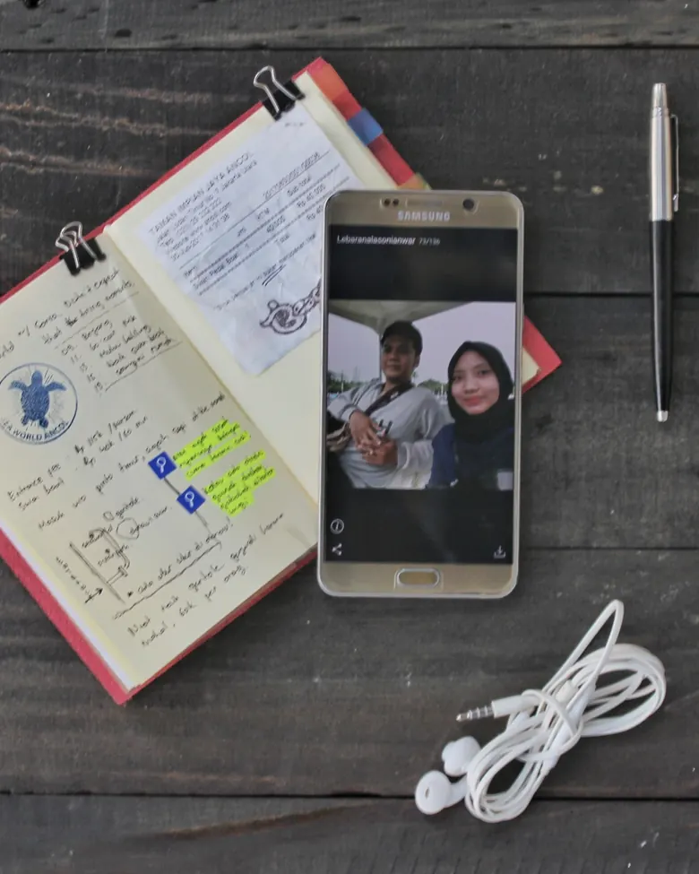 Jurnal lini Line Hibrkraft di samping smartphone dan earphone