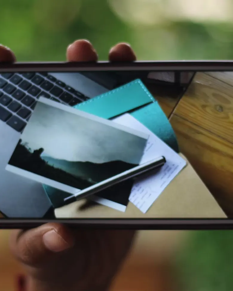 Smartphone menampilkan setup meja kerja di samping jurnal kulit