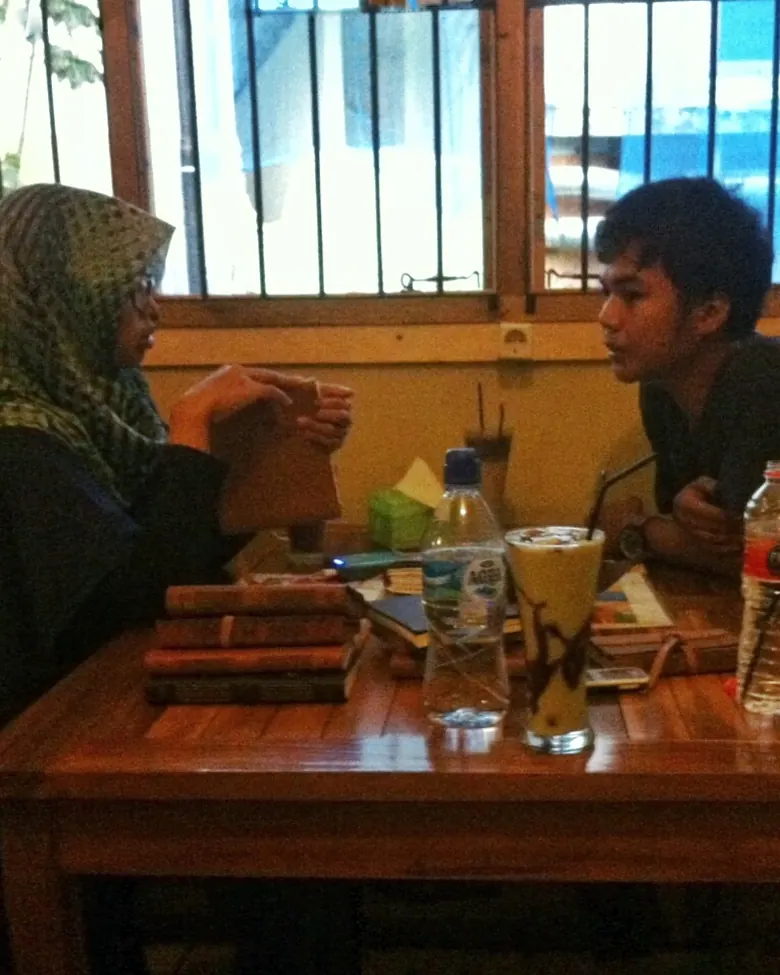 Dua orang mendiskusikan jurnal kulit sambil memegangnya