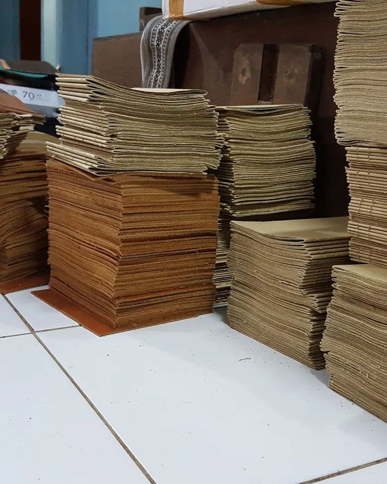 Tumpukan lembar kertas di bengkel, disiapkan untuk pesanan massal.