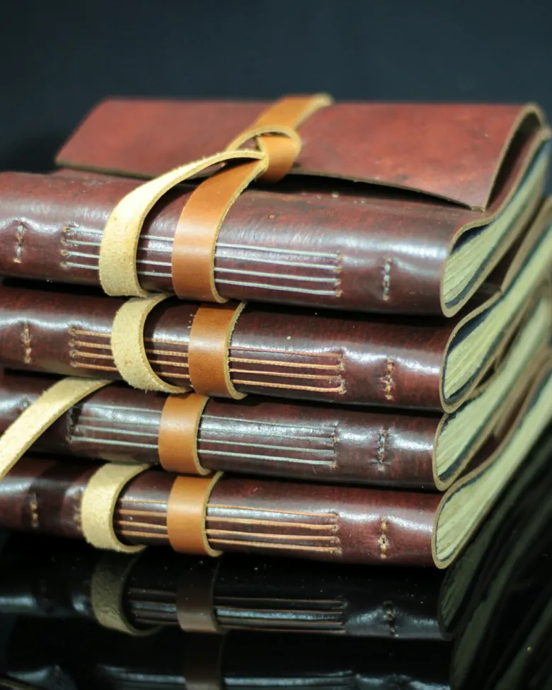 Leather journals with an elastic closure strap, stacked and ready to ship