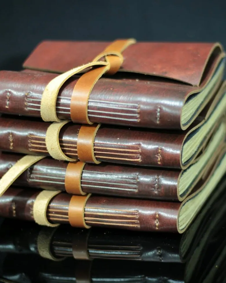 Leather journals stacked squarely, showing spine and page-edge detail