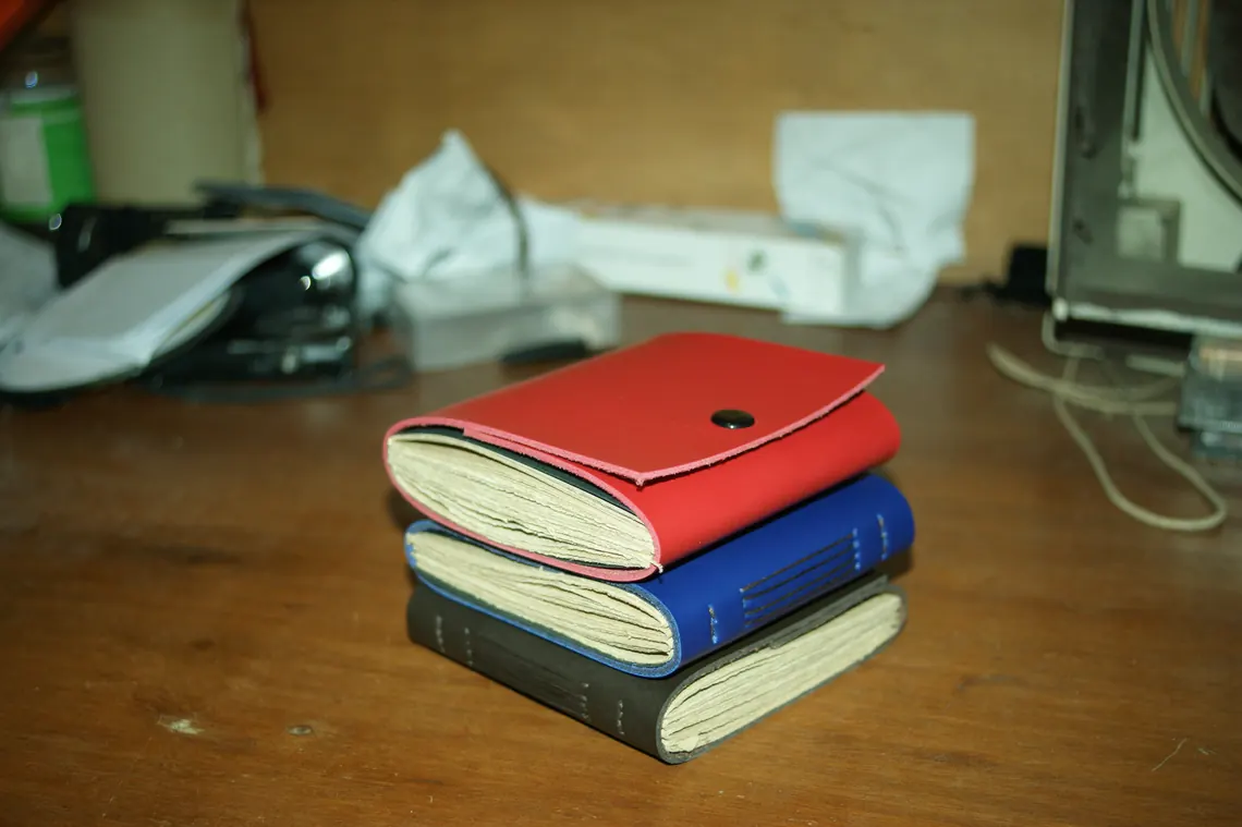 Stacked leather journals on a workshop desk during production