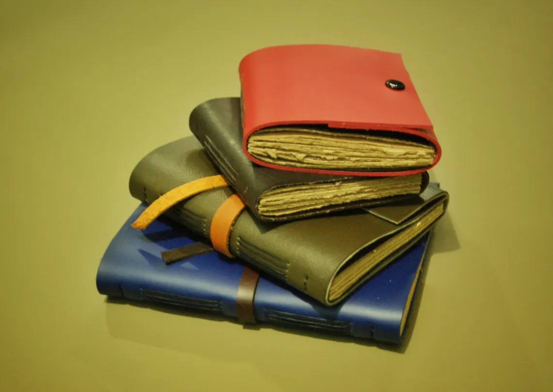 Stacked leather journals with deckled paper edges visible at the page block