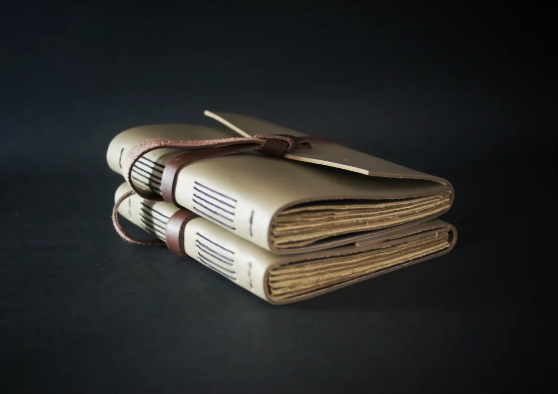 Two leather journals stacked with wraparound leather ties as closures