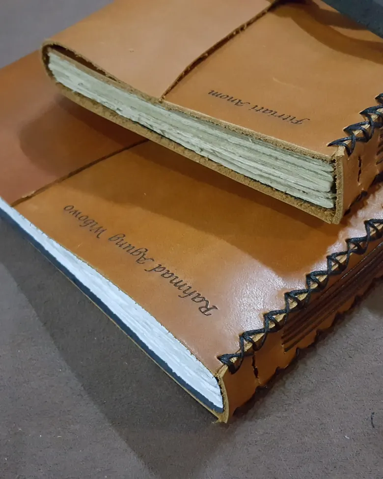 Jurnal kulit dengan nama penerima yang di-deboss pada sampul depan.