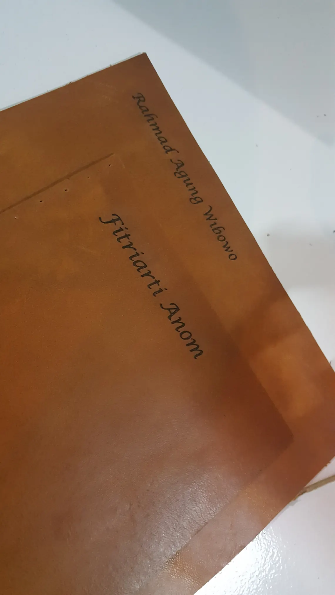 Sampul kulit dengan beberapa nama penerima berbeda tercetak berurutan.