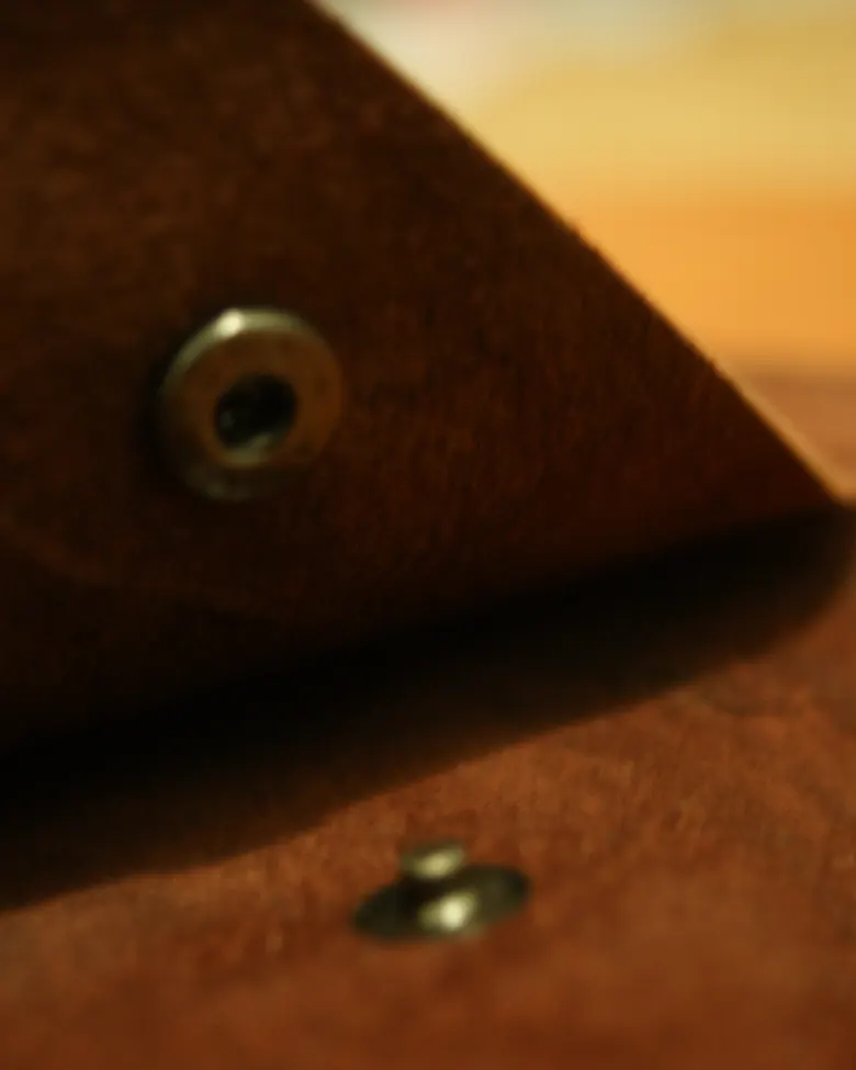 Detail kancing snap kuningan pada penutup jurnal kulit suede