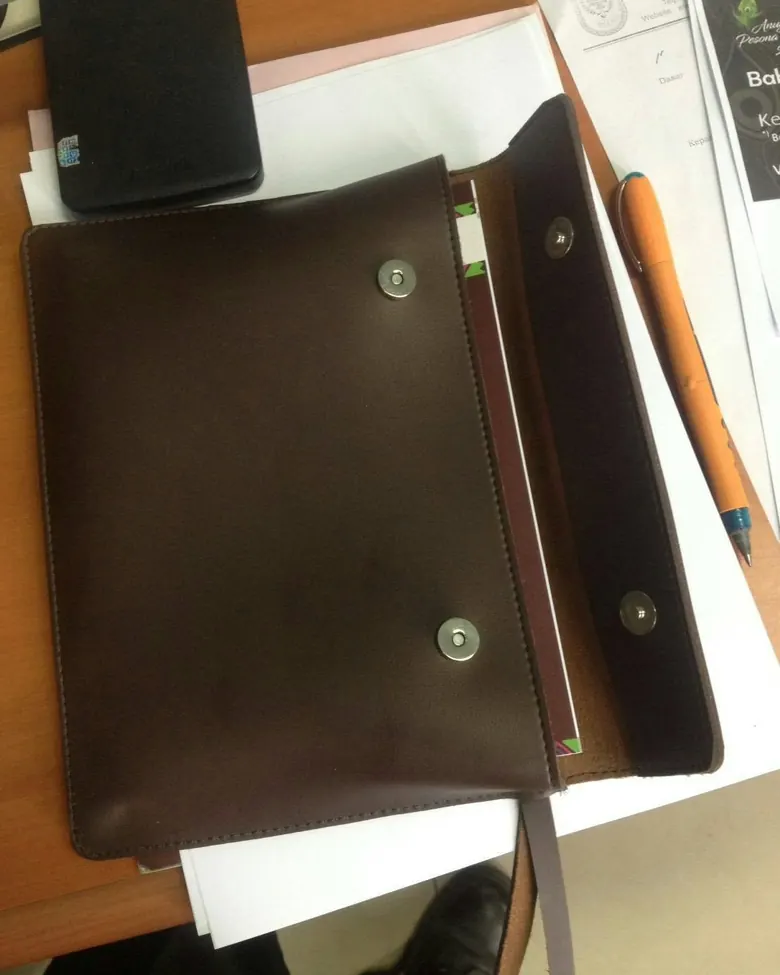 Jurnal kulit cokelat dengan kancing magnetik.