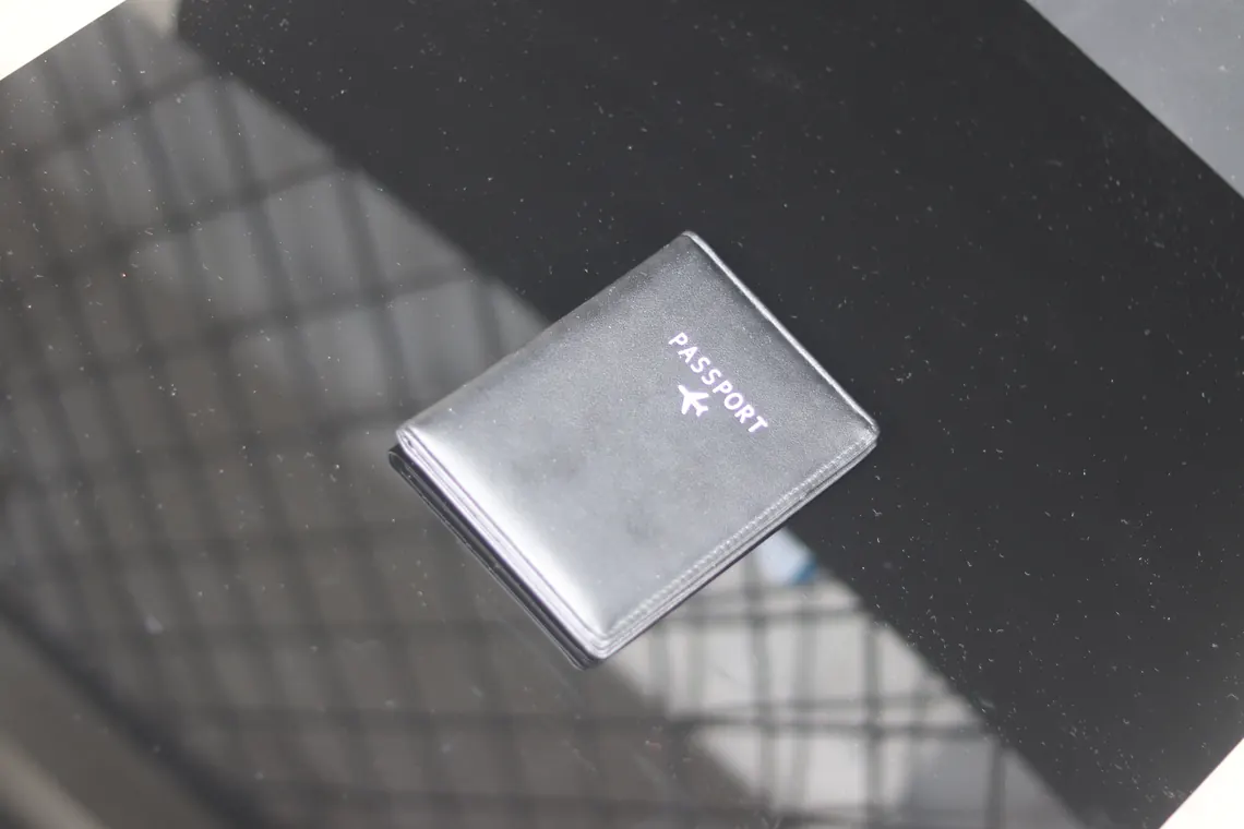 Dompet paspor kulit hitam tanpa logo yang mencolok, tampilan close-up.