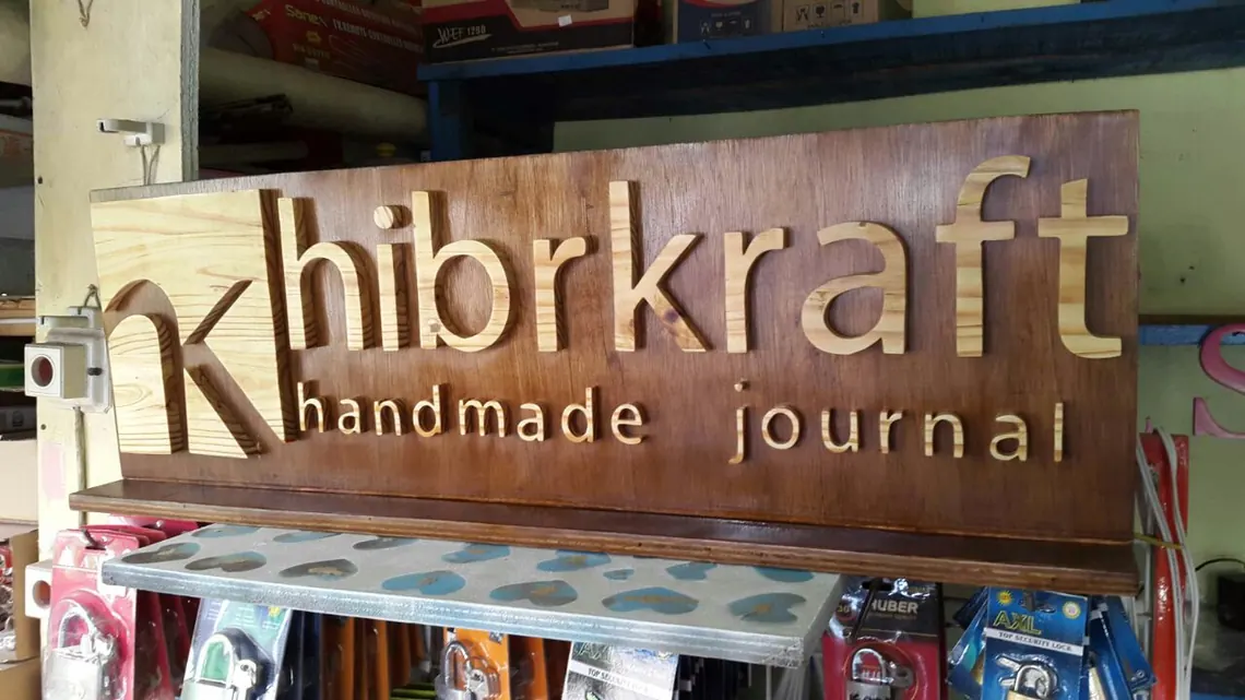 Papan nama kayu Hibrkraft terpasang di dinding bengkel