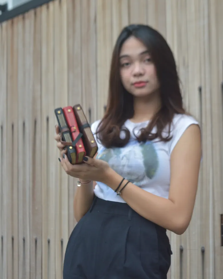 Seseorang memegang tiga jurnal kulit dengan warna berbeda.