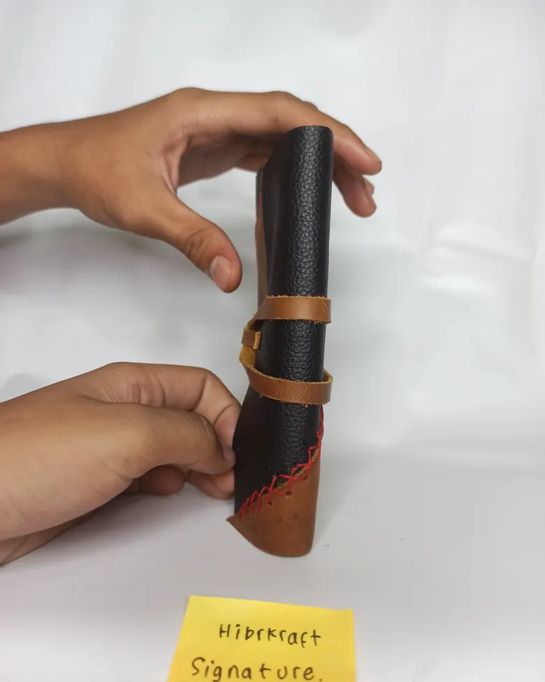 Tangan memegang pouch kulit Hibrkraft yang digulung
