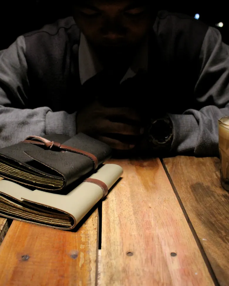 Tumpukan jurnal kulit Hibrkraft di atas meja kayu