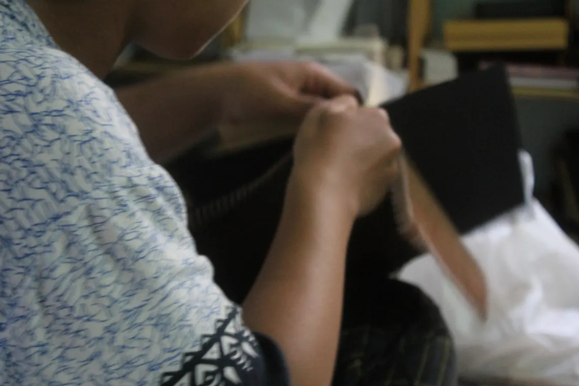 An artisan hand-stitching a leather journal cover.